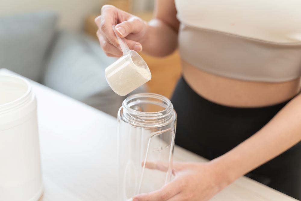 Woman putting casein protein powder into a shaker