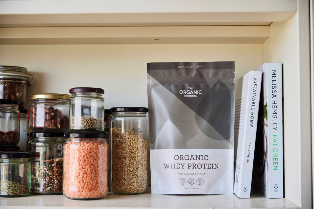 Protein powder on a kitchen shelf with other store cupboard ingredients