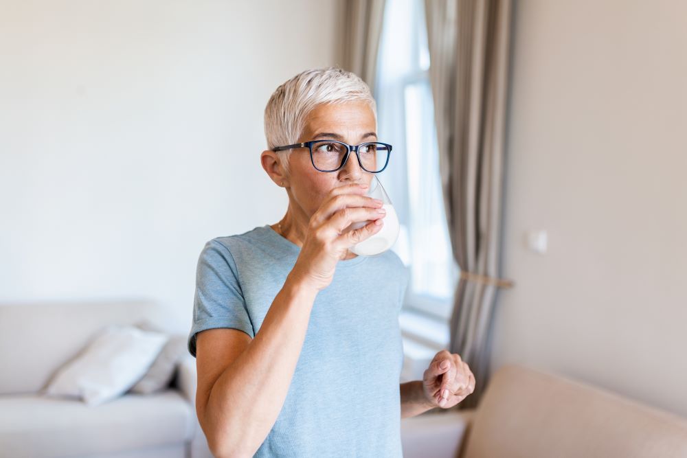 A woman drinking  a glass of milk with protein powder