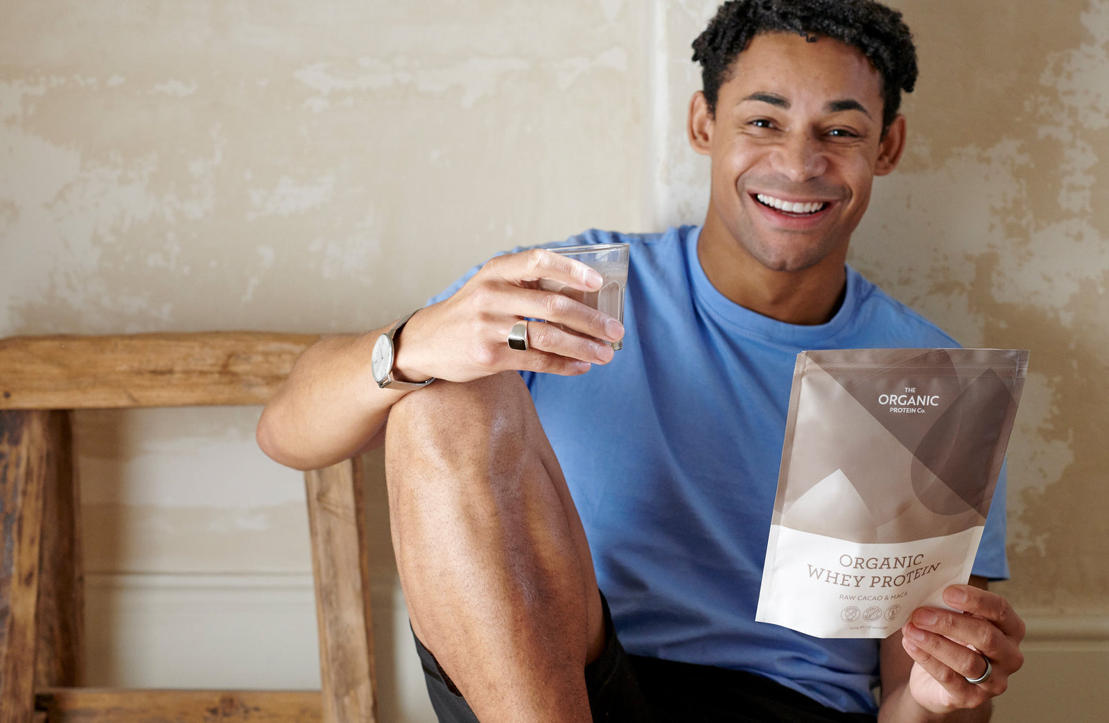 A man with a glass of The Organic Protein Co.'s organic whey protein powder