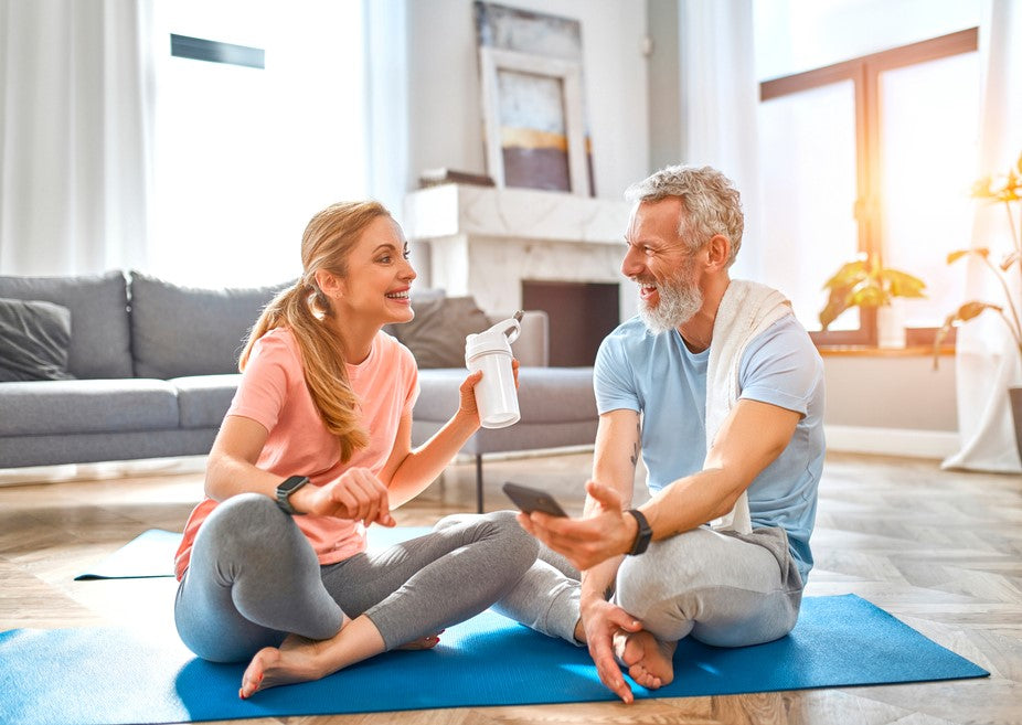 A healthy, mature couple sat together on a yoga mat